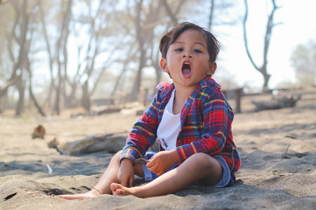 Happy kids have fun in sea surf on black sand beach. Children sit in seashore. Travel lifestyle, swimming activities in family summer camp. Vacations on tropical island.の写真素材