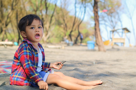 Happy kids have fun in sea surf on black sand beach. Children sit in seashore. Travel lifestyle, swimming activities in family summer camp. Vacations on tropical island.の写真素材