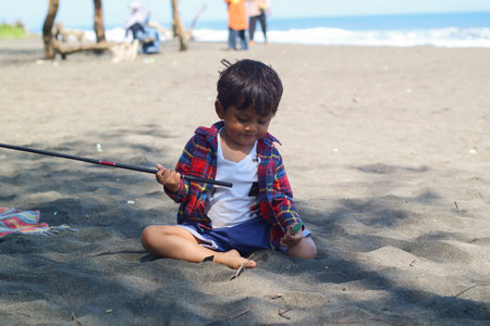 Happy kids have fun in sea surf on black sand beach. Children sit in seashore. Travel lifestyle, swimming activities in family summer camp. Vacations on tropical island.の写真素材
