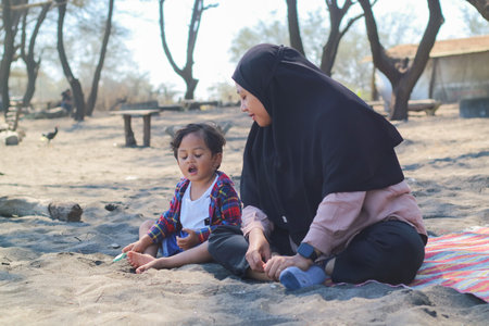 Happy baby boy and mother play sand and toy together on the beach.の写真素材
