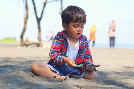 Happy kids have fun in sea surf on black sand beach. Children sit in seashore. Travel lifestyle, swimming activities in family summer camp. Vacations on tropical island.の写真素材