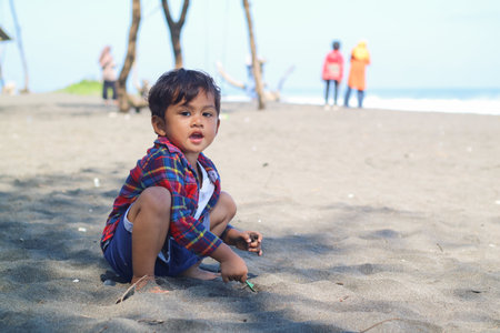 Happy kids have fun on black sand beach. Children sit in seashore. Travel lifestyle, swimming activities in family summer camp. Vacations on tropical island.の写真素材