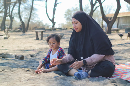 Happy baby boy and mother play sand and toy together on the beach.の写真素材