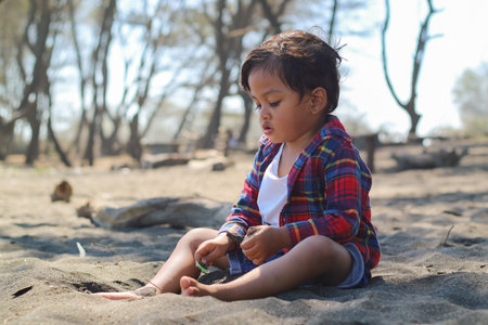 Happy kids have fun in sea surf on black sand beach. Children sit in seashore. Travel lifestyle, swimming activities in family summer camp. Vacations on tropical island.の写真素材