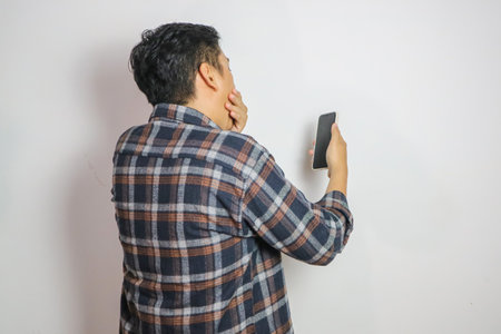 Back view of a man shock cover mouth with hand looking to the mobile phone that he hold