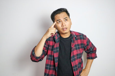 Adult Asian man pointing to his temple with confused expression