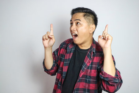 Young Asian man in a plaid shirt on a white background.
