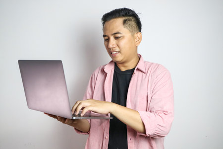 Young Asian business man using laptop computer and sitting on white chair isolated on white...