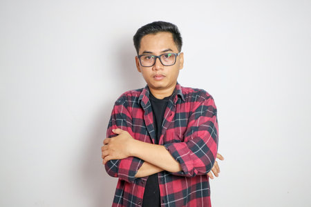 Young Asian man wearing glasses and a plaid shirt on white backgroundの写真素材