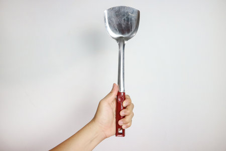 Female hand hold spatula. Isolated on a white background . High quality photoの写真素材
