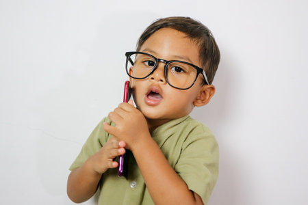 Happy Asian portrait cute young kid boy smiling excited talking smart mobile phone studio shot...