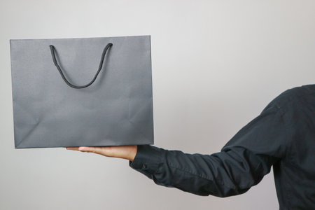 hand asian men in stylish outfit carrying a lot of purchases, black shopping paper bags over white studio background. concept of fashion, beauty, salesperson, Black Friday, sale. copy space. adの写真素材
