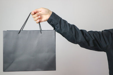 men hand holding craft shopping bag with Black Friday on white background. Sale, discount, shopping conceptの写真素材