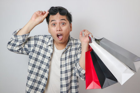 Funny surprised and shocked face of Asian man see product in the shopping bagの写真素材