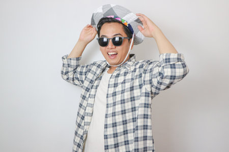 Overjoyed asian man wearing sunglasses dancing, makes movements to music, smiles positively, being in high spirit. isolated on blue background. holiday and vacation conceptの写真素材