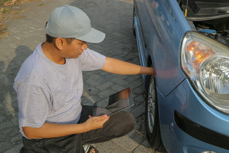 Expertise mechanic man in uniform using force trying to unscrew the wheel bolts nuts and help a woman for changing car wheel on the highway, car service, repair, maintenance concept.の写真素材