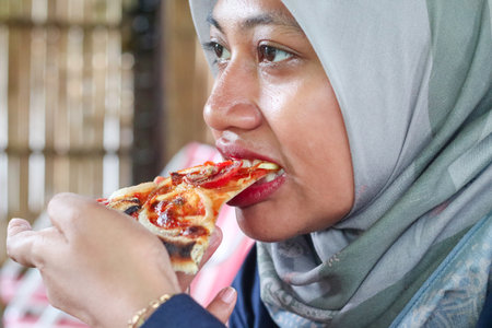 happy young muslim hijab women eating pizzaの写真素材