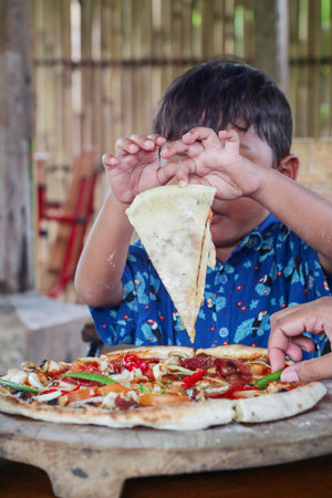 Little kid enjoys eating pizza.の写真素材