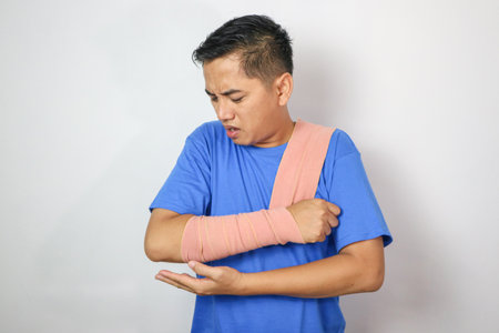 Young man with hand injured wearing splint, broken arm, isolated on white background
