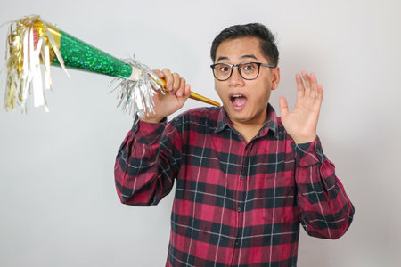 Asian young man blowing a horn while celebrating new year