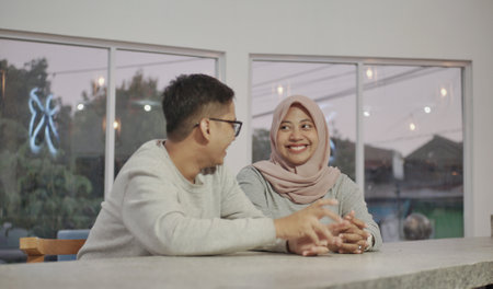 Asian husband and wife sitting and joking on the living roomの写真素材