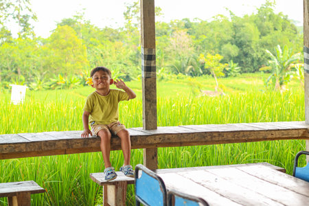 asian kids 4 year old child sitting on a bench with a natural rice field atmosphere, holiday concept in Baliの写真素材