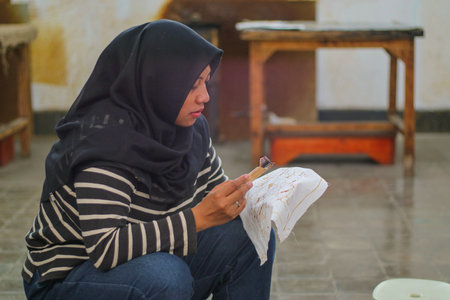 Young Indonesian women or fashion models wearing traditional Indonesian clothing or attire with batik motifs from Indonesian culture. Making or painting batik cloth. Making batik cloth.の写真素材