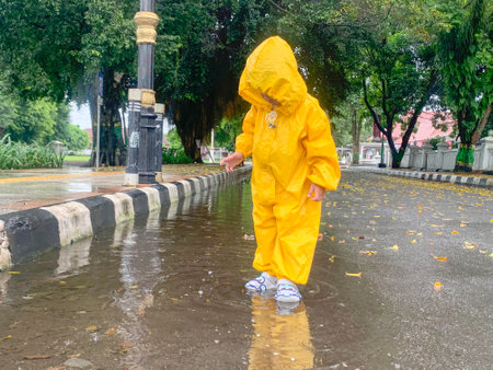 Boy in yellow raincoat playingの写真素材
