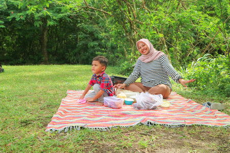 Happy cheerful Asian muslim family living together in a weekend, woman muslim embracing her lovely little son and smiling to camera. Modern muslim lifestyles concept.の写真素材