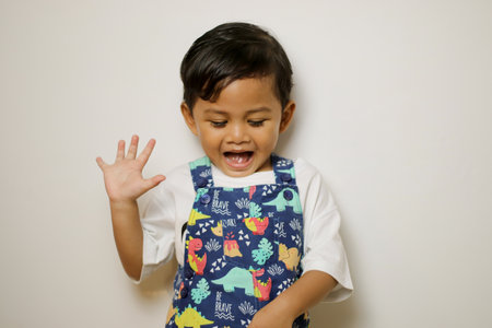 Happy Asian little boy hands up raised arms from happiness isolated on white background, Excited kid...