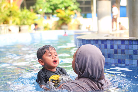 A Happy mother and son are enjoy swimming in pool , lifestyle, parenthood, family concept .