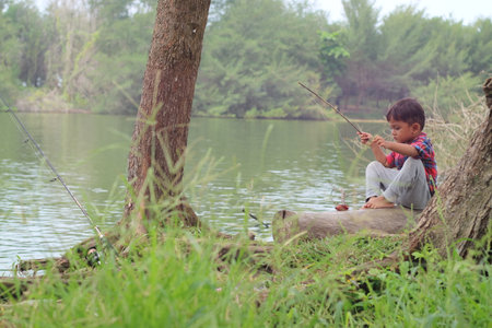 Little boy fishing on the river bank in the countryside.の写真素材