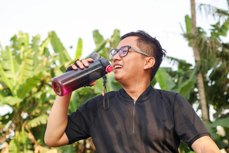 Young Asian man drinking water after a workout in the park. Healthy lifestyleの写真素材