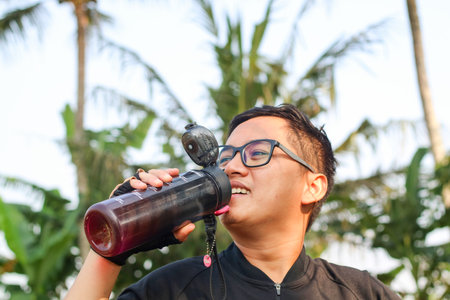 Asian young man drinking water after jogging