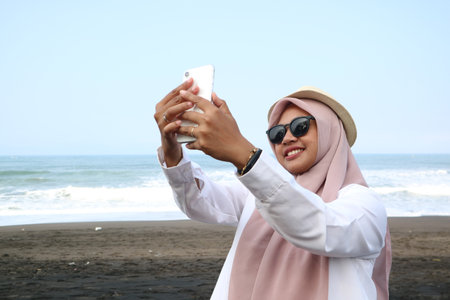 happy beautiful woman with scarf take picture of her self using smartphone