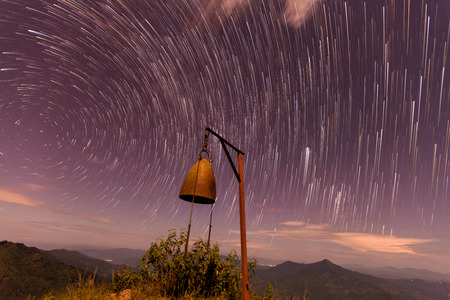 The Stars night of startails rises over the mountain and the bell in Thailand.Long exposure photograph.の写真素材