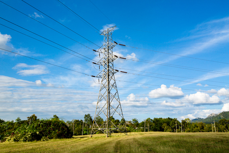 High voltage lines and power pylons in a flat and green agricultural landscape with cirrus clouds on blue sky, Mea Moh, Lampang, Thailand.の写真素材