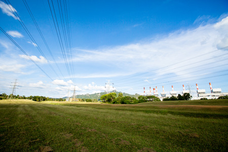 High voltage lines and power pylons in a flat and green agricultural landscape with cirrus clouds on...