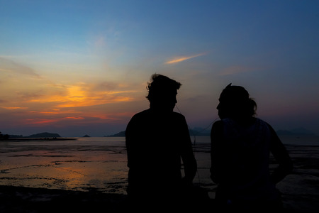 Romantic couple on the beach at sunset on background.の写真素材