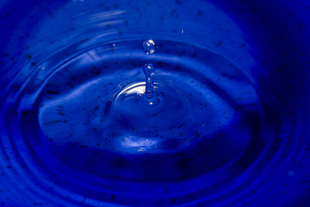 Water drop in dark blue texture color flying from aboveの写真素材