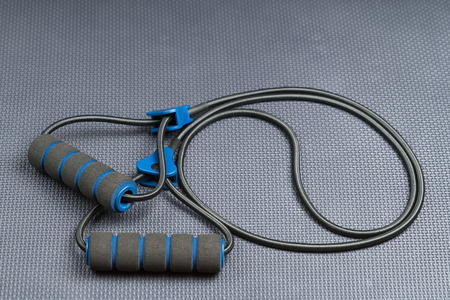 Black elastic exercise resistance band cord on a weight training gym floor with text / writing space. Cord coiled in the shape of the yin yang balance symbol.の写真素材