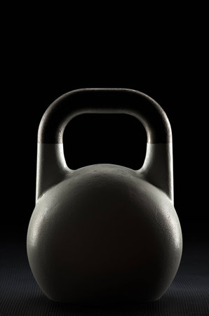 Backlit competition kettlebell silhouette on a fitness studio gym floor with potential text / writing / copy space on and above kettlebellの写真素材