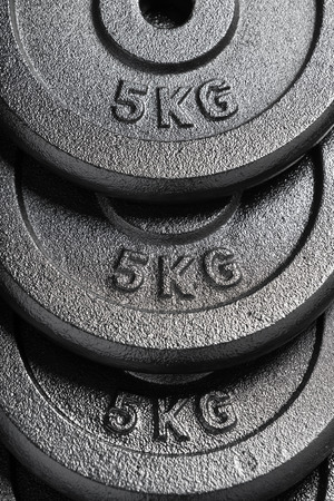 Stack of 5kg barbell / dumbbell weight plates inside a weightlifting gymの写真素材