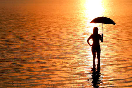 silhouette of young woman against summer sunsetの写真素材