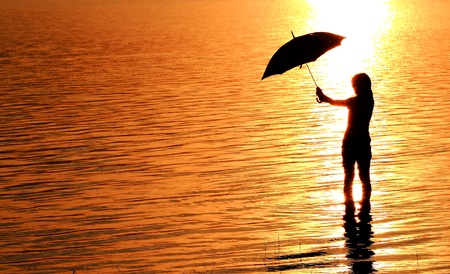 silhouette of young woman against summer sunsetの写真素材