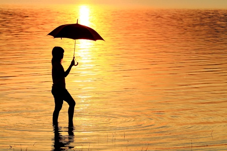 silhouette of young woman against summer sunsetの写真素材