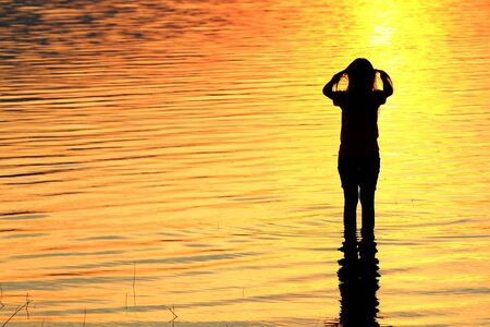 Silhouette of a girl in the water at sunsetの写真素材