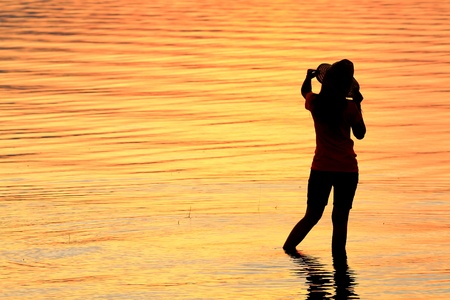 Silhouette of a girl in the water at sunsetの写真素材