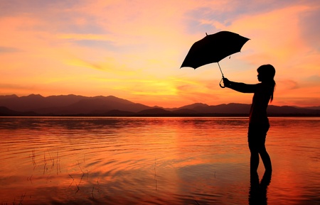 silhouette of young woman against summer sunsetの写真素材
