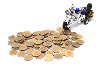 Motorcycle over a lot of golden coins (isolated on white)の写真素材
